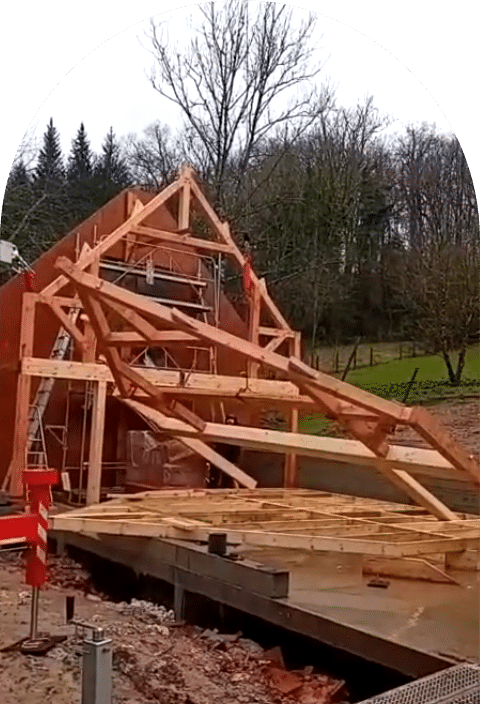 Une extension en construction avec des poutres en bois, illustrant une ossature bois traditionnelle