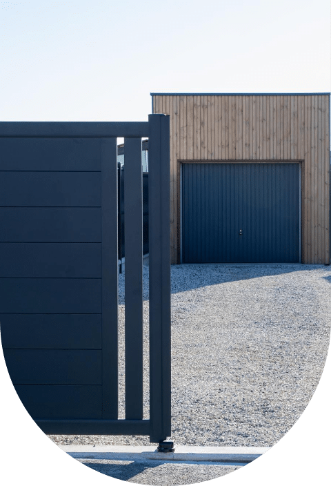 Une porte de garage noire adossée à une clôture en bois