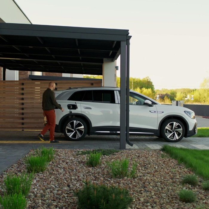 Un homme se tient à cote d un SUV blanc dans un carport en Normandie