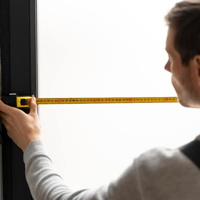 Un homme mesure la taille d une fenêtre en aluminium pour son installation