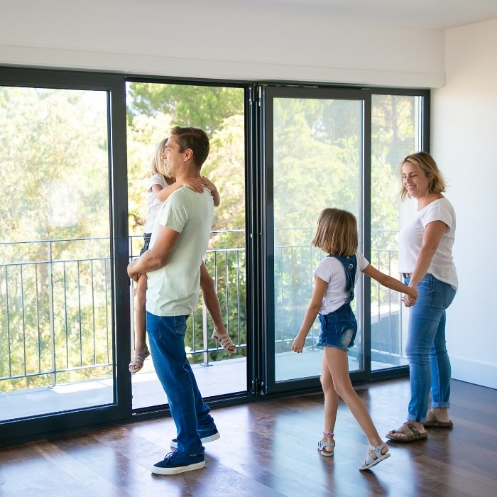 Une famille se tient devant une porte fenêtre en PVC