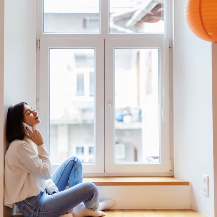 Une femme assise sur le sol, à côté d une fenêtre en PVC