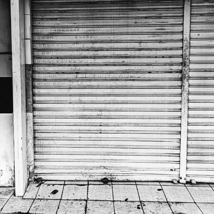 Photo en noir et blanc d une porte de garage fermée, mettant en avant sa texture et son design minimaliste