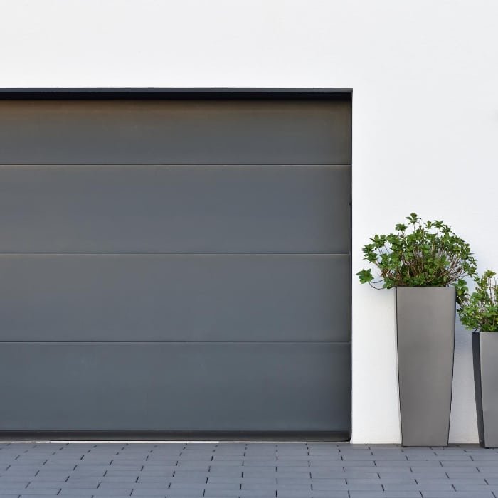 Porte de garage avec deux jardinières de chaque côté, ajoutant une touche décorative à l entrée
